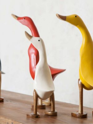 Trzy kaczki w różnych kolorach odwrócone kuprami do obiektywu.