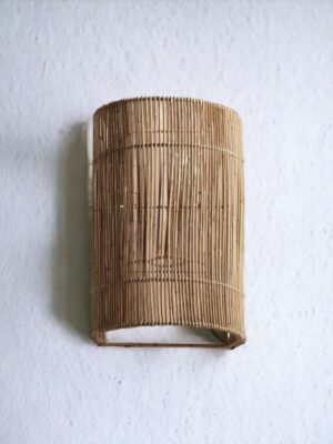 Kinkiet z rattanu Plia na białej ścianie.