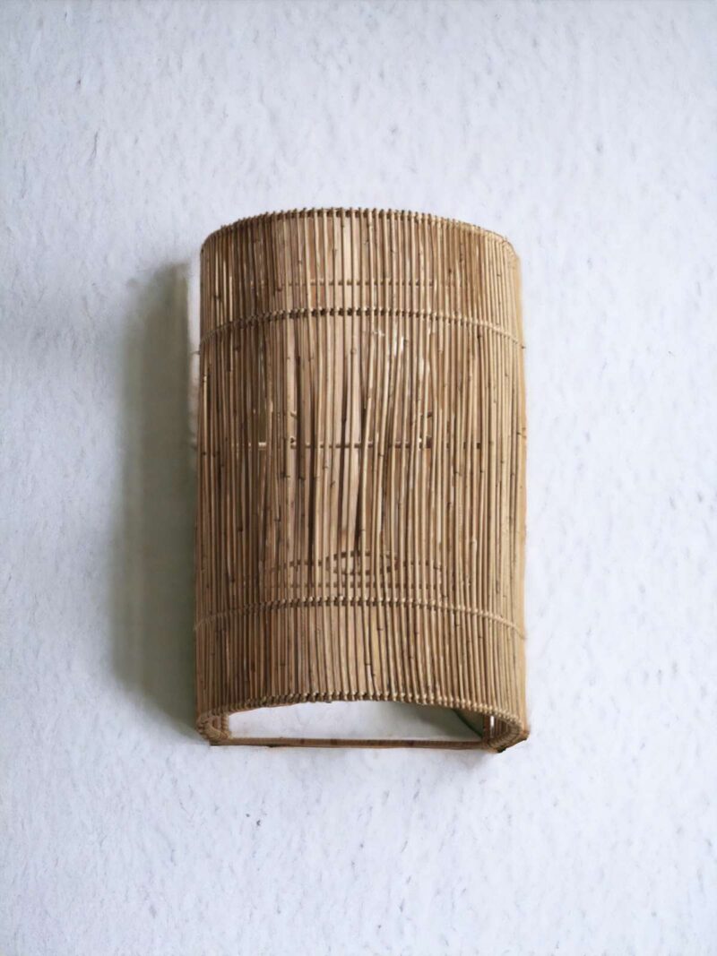 Kinkiet z rattanu Plia na białej ścianie.