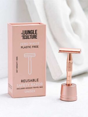 Maszynka do golenia na żyletki różowa metalowa na stojaku.