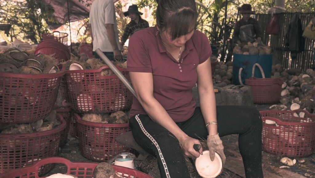 Pani w Wietnamie rzeźbi miskę z kokosa.
