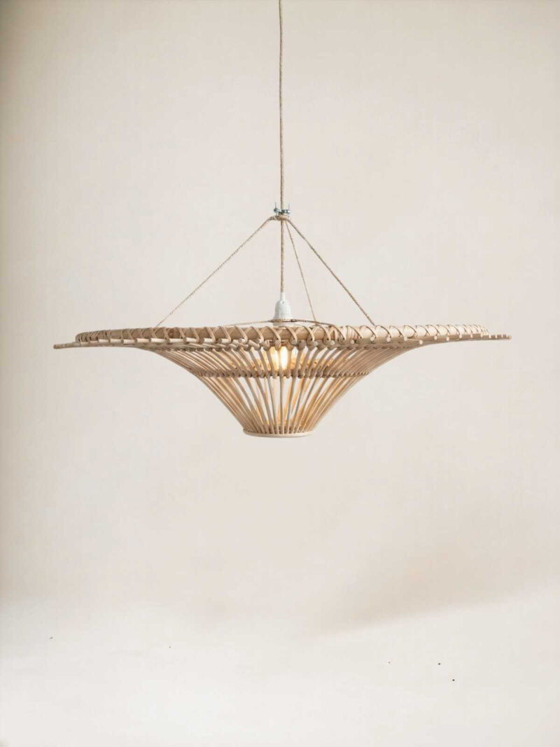 Duża rattanowa okrągła lampa wisząca w kształcie bączka na jasnym tle.