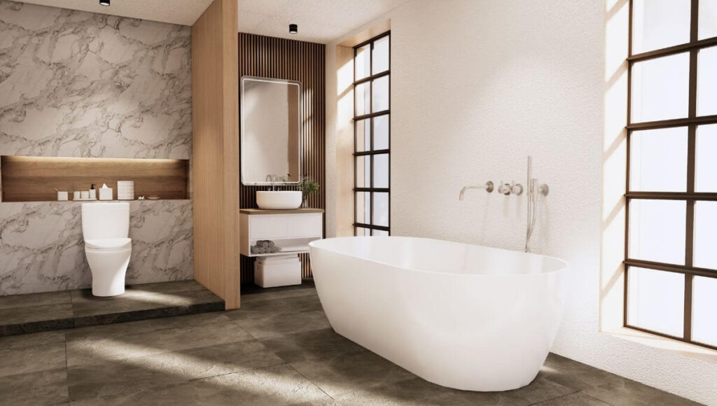 Na zdjęciu widać białą wannę, duże lustro zawieszone na ścianie z drewnianych paneli i toaletę na ścianie wykonanej z jasnego kamienia. Łazienka urządzona w stylu japandi.