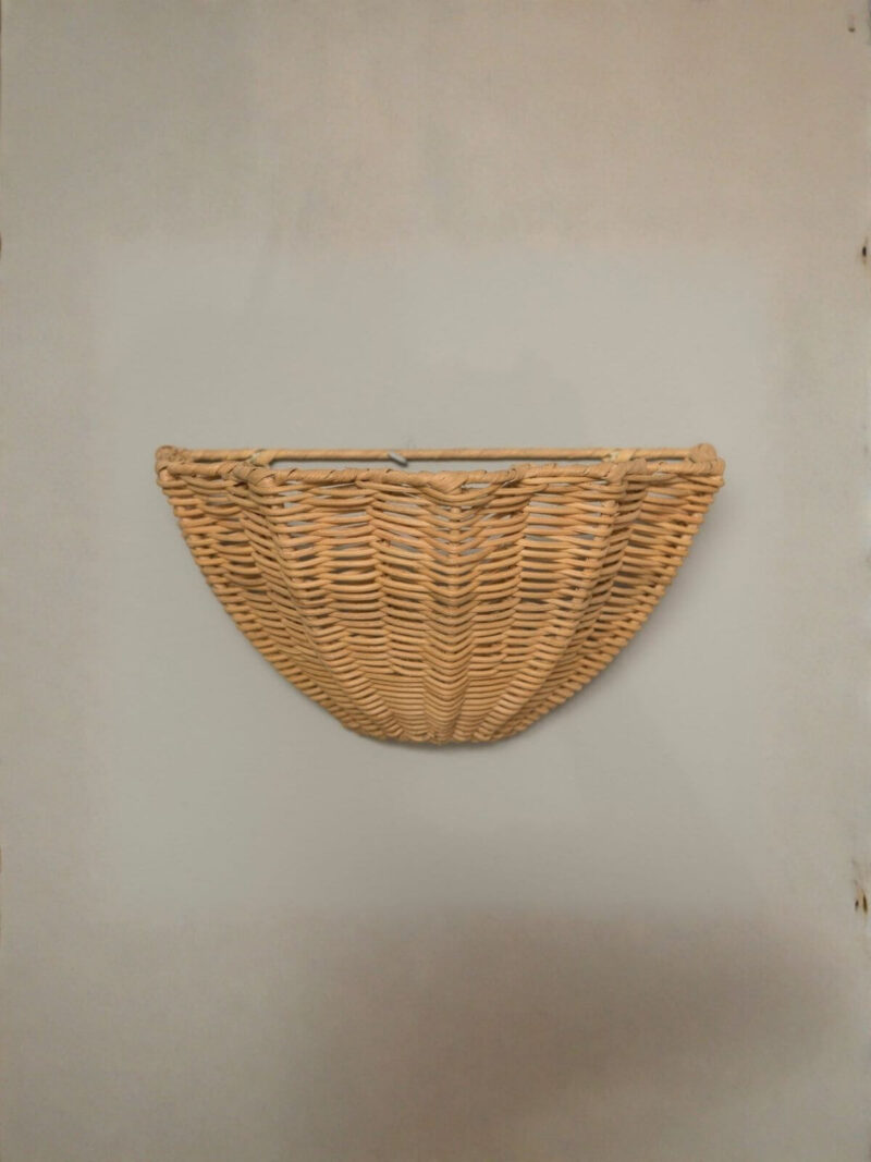 Kinkiet fale Waves z rattanu na tle jasnej ściany.