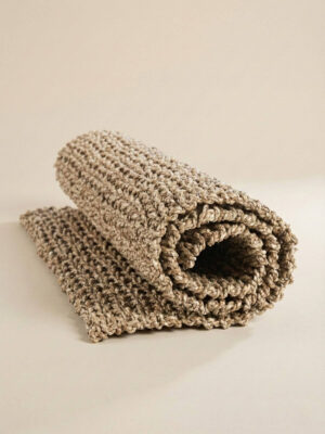 Chodnik sizalowy zwinięty w rulon na jasno-beżowym tle.