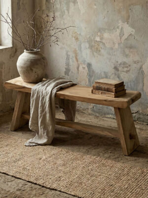 Ławka drewniana boho na tle surowej betonowej ściany.