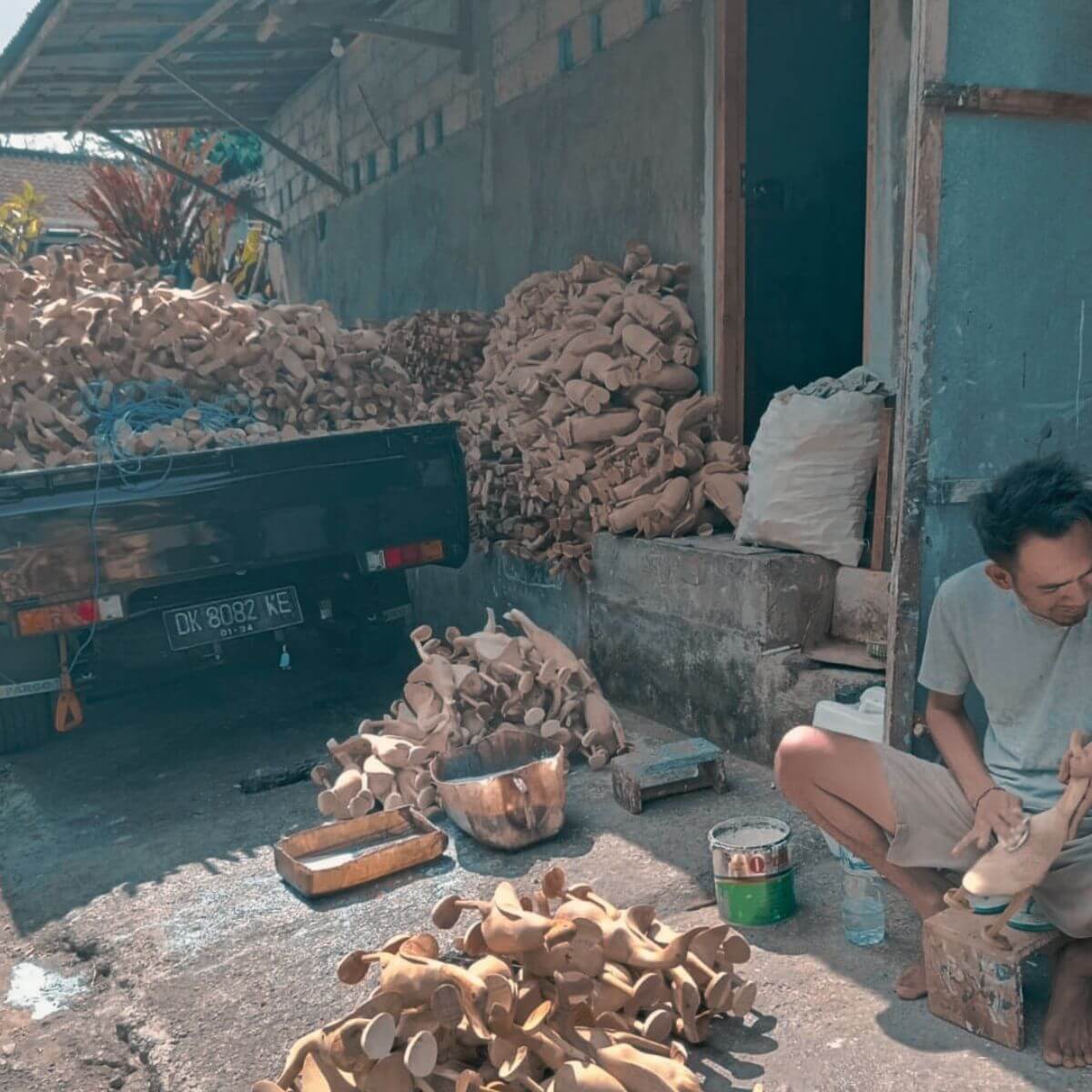 Drewniane kaczki z Bali na ciężarówce a obok rzemieślnik rzeźbi jedną z takich kaczek.