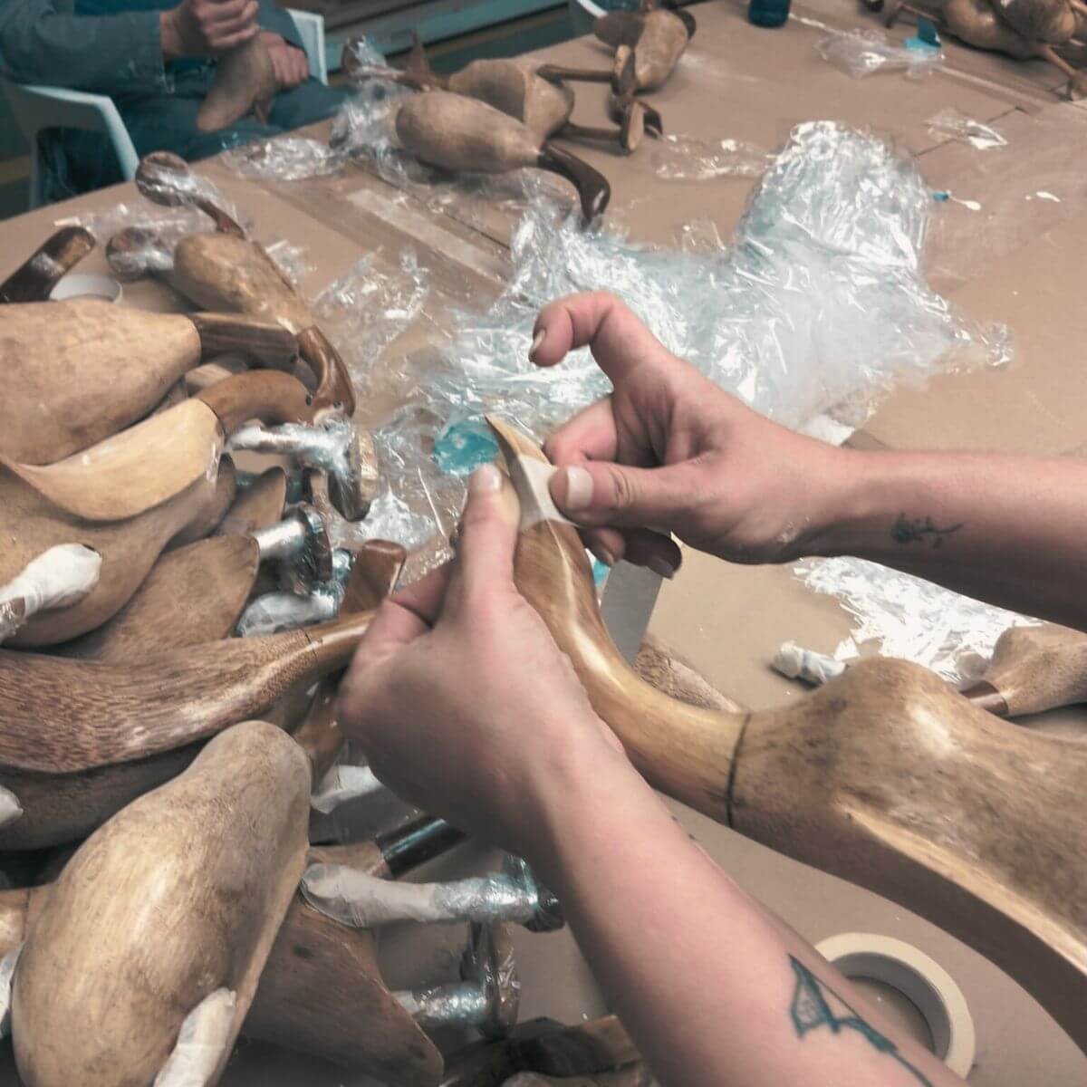 Rzemieślnik rzeźbi dziób drewnianej figurki kaczki.