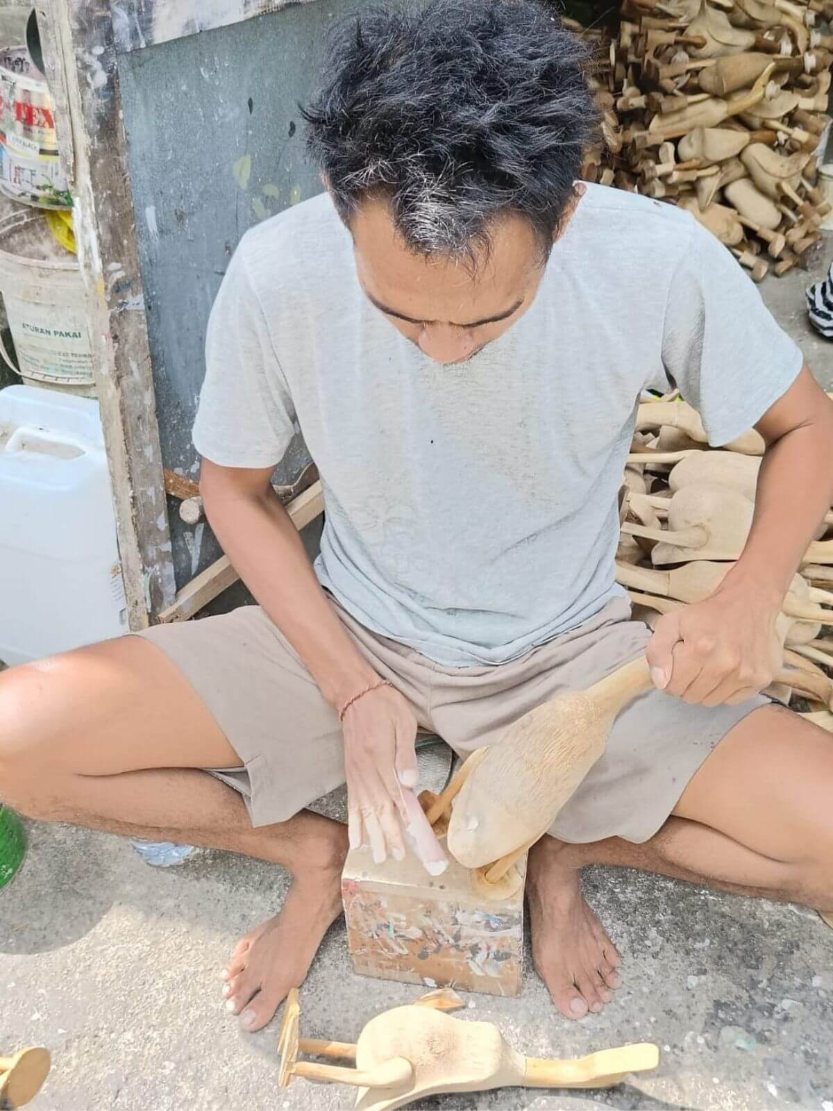 Mężczyzna szlifuje drewnianą kaczkę balijską.